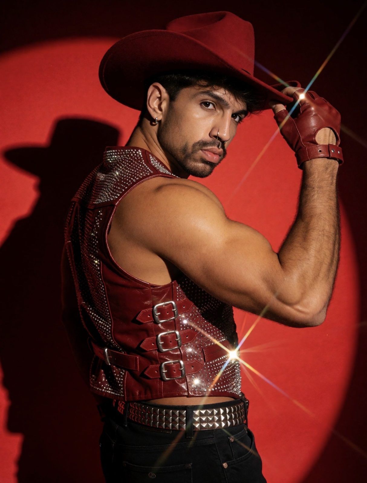 Joy Terra de colete de couro vermelho com strass, olhando por cima do ombro sob um holofote